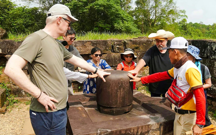 Tour group examining ancient artifact at My Son Sanctuary, Vietnam.
