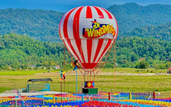 Hot air balloon at De Windmill Selfie Park, Langkawi, with colorful pinwheels and scenic mountain backdrop.