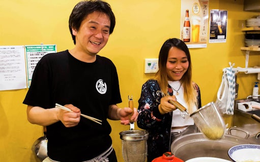 People cooking noodles in a ramen kitchen experience.