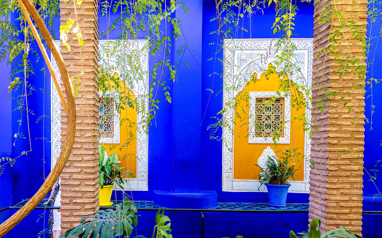 Jardin Majorelle's vibrant blue and yellow walls with intricate window designs and lush greenery.