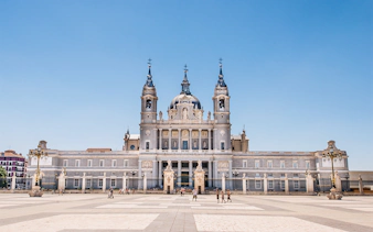 Almudena Cathedral facade in Madrid, Spain, with tourists in the foreground.