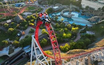 Roller coaster at Vialand Theme Park, Istanbul, with riders on a steep red track.