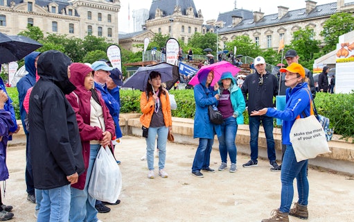 Tour group with guide near Notre Dame de Paris, umbrellas open, during outdoor walking tour.