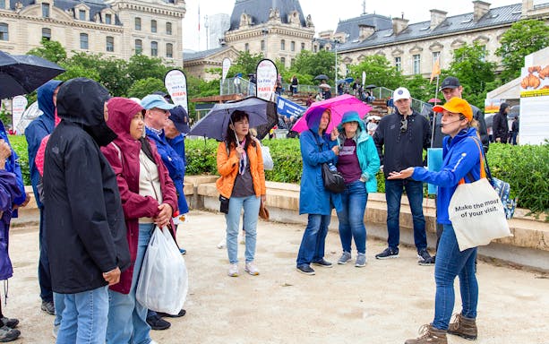 Tour group with guide near Notre Dame de Paris, umbrellas open, during outdoor walking tour.