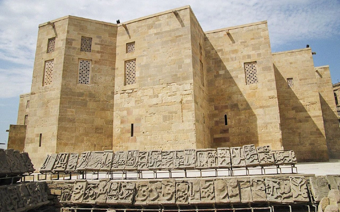 Palace of Shirvanshahs in Baku with intricate stone carvings in the foreground.