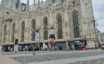 Two people jumping in front of Milan Cathedral during a self-guided city exploration game.