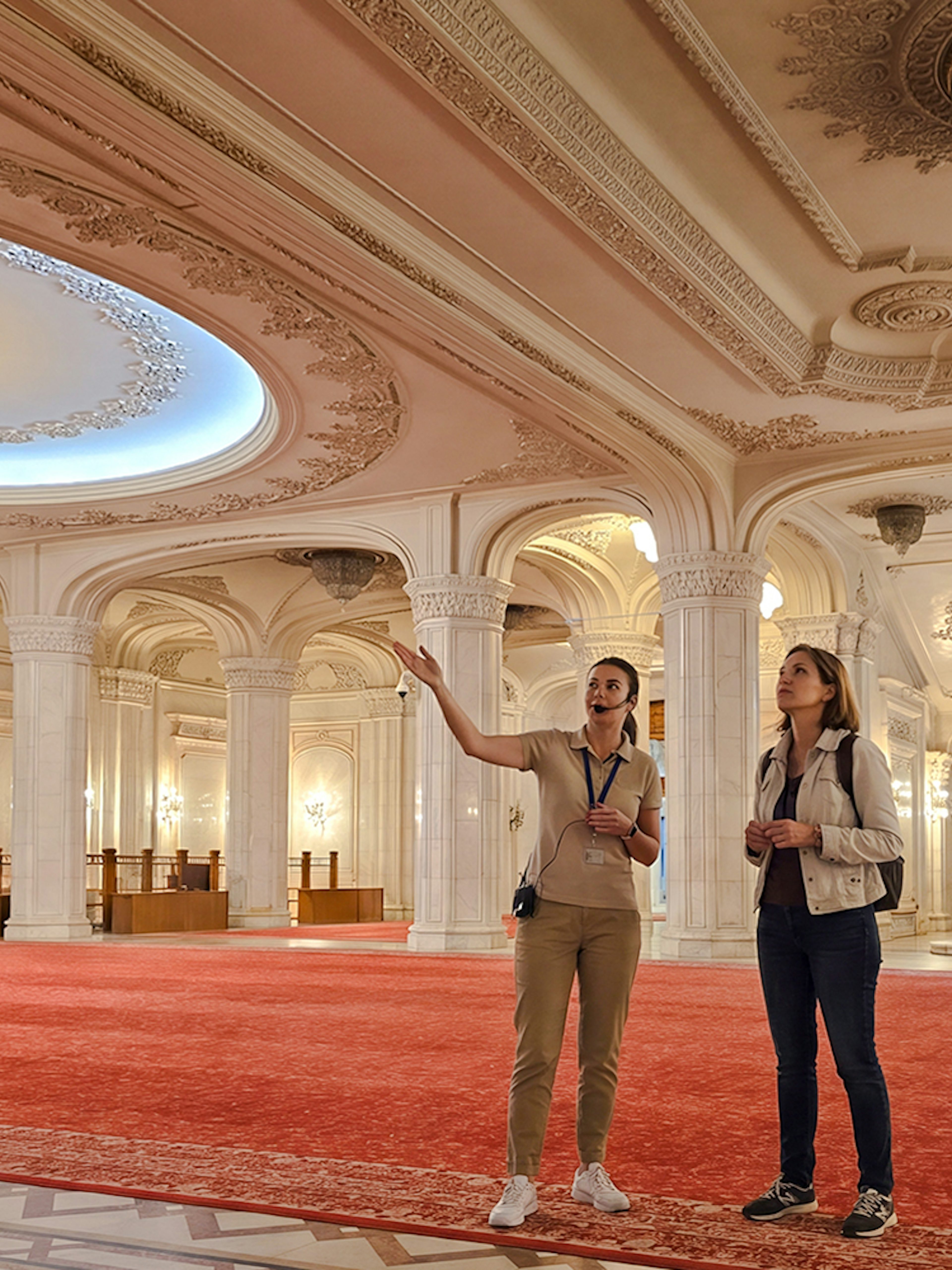 Tourists exploring ornate hall with chandeliers, Palace of Parliament, Bucharest.