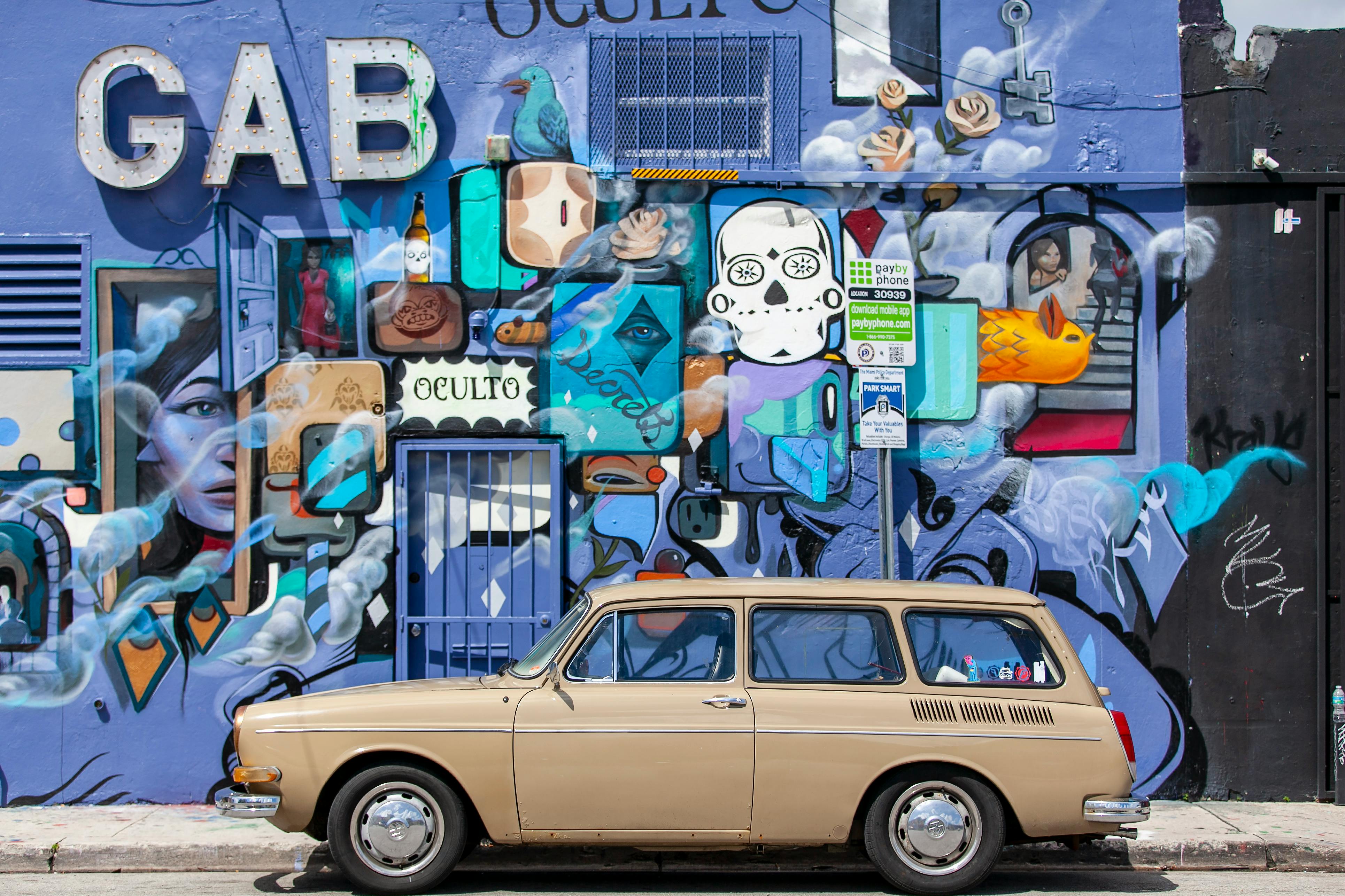 Mural featuring vibrant graffiti art on Wynwood Walls, Miami, with a vintage car in front.