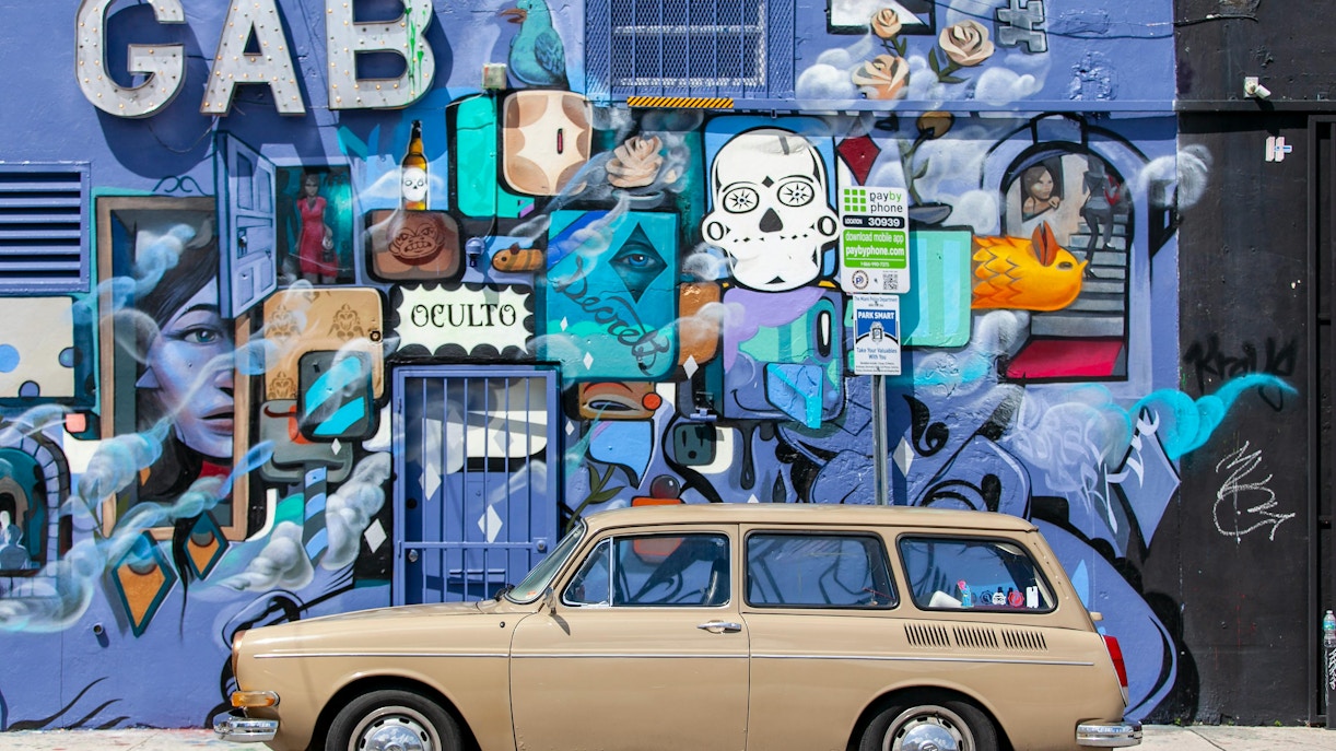 Mural featuring vibrant graffiti art on Wynwood Walls, Miami, with a vintage car in front.