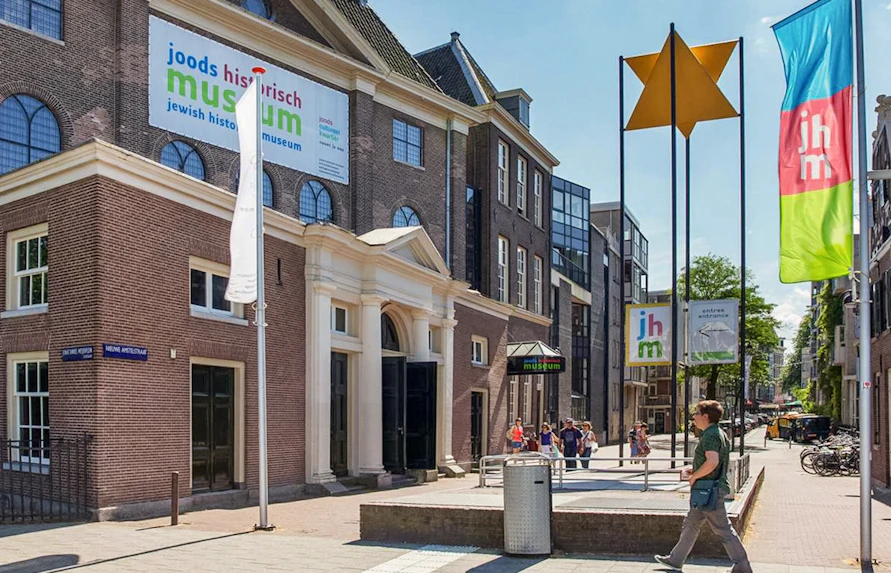 Exterior of Jewish Historical Museum in Amsterdam with entrance and flags.