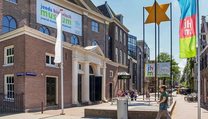 Exterior of Jewish Historical Museum in Amsterdam with entrance and flags.
