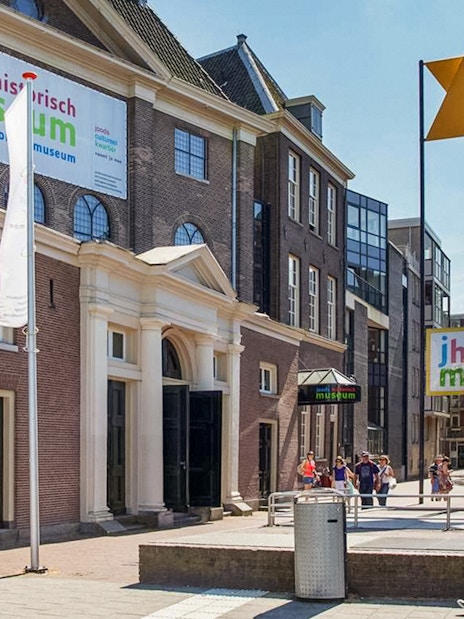 Exterior of Jewish Historical Museum in Amsterdam with entrance and flags.
