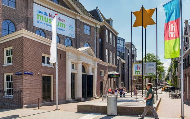 Exterior of Jewish Historical Museum in Amsterdam with entrance and flags.