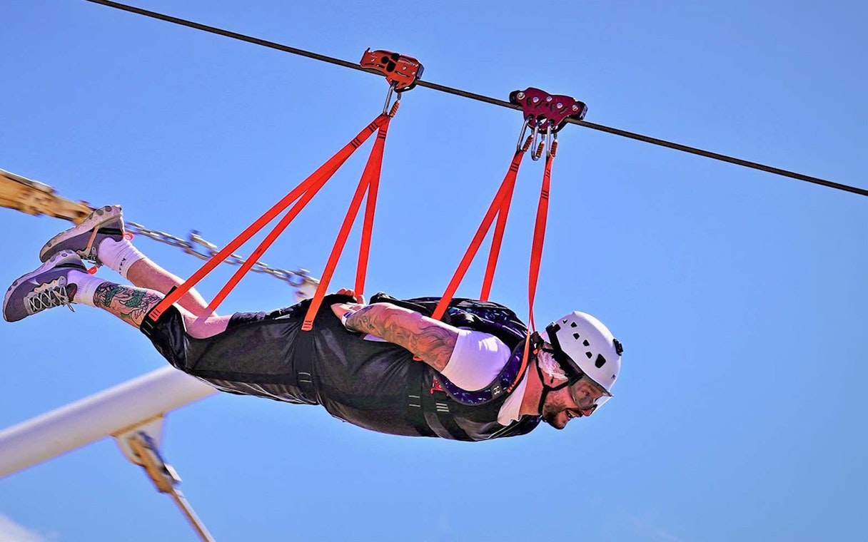 Person ziplining on Jebel Jais, Ras Al Khaimah, wearing safety gear.