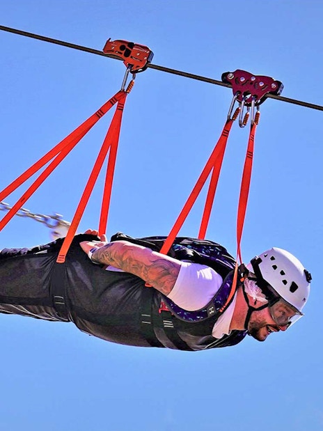 Person ziplining on Jebel Jais, Ras Al Khaimah, wearing safety gear.