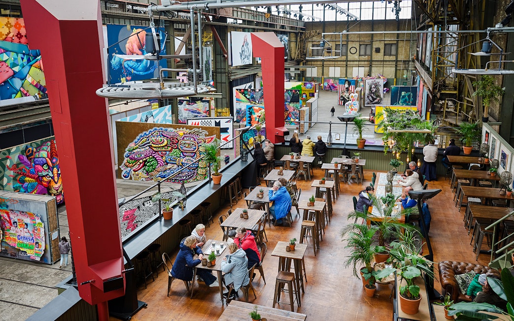 Cafe seating area inside Straat Museum with vibrant street art displays.