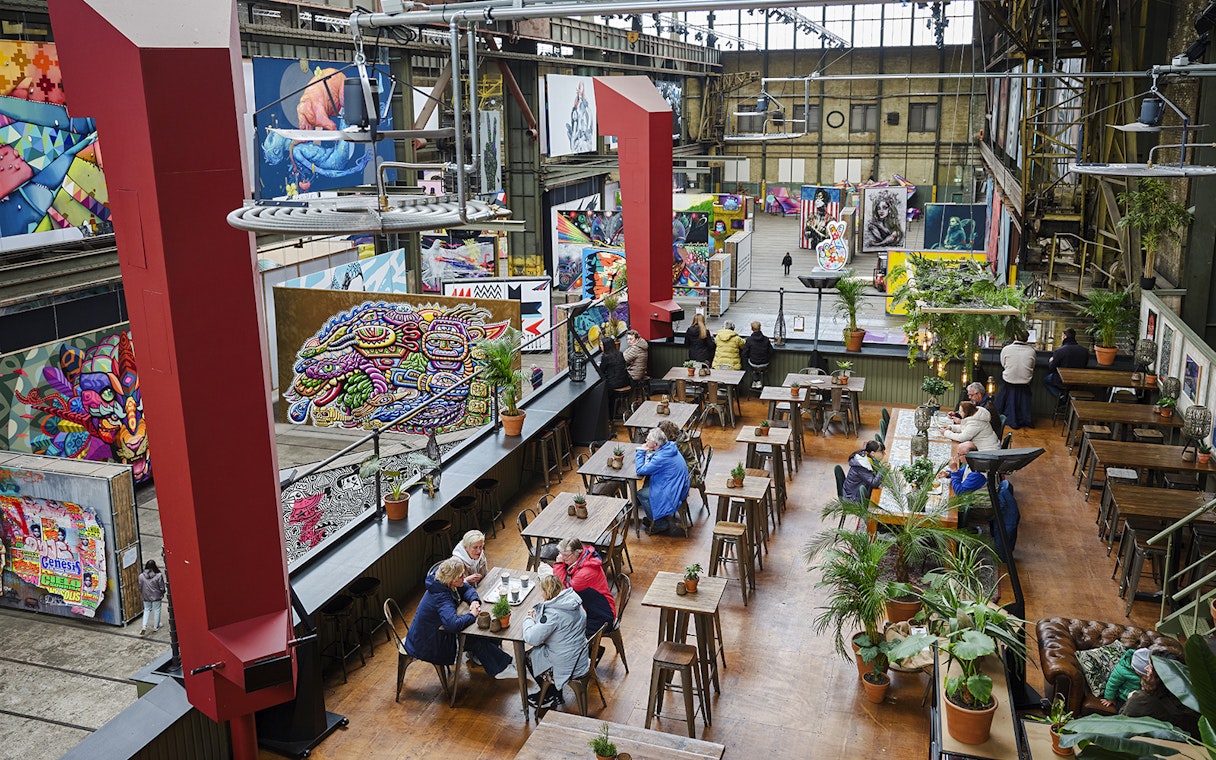 Cafe seating area inside Straat Museum with vibrant street art displays.