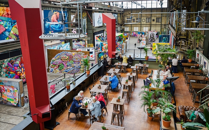 Cafe seating area inside Straat Museum with vibrant street art displays.