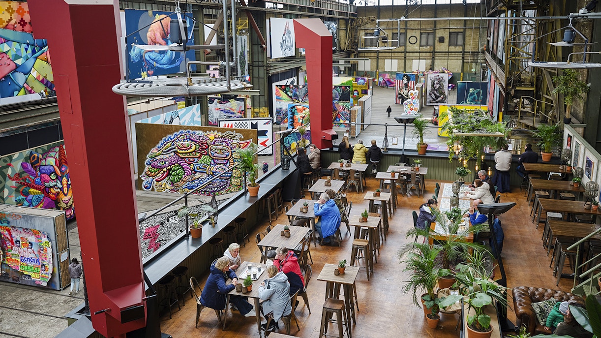 Cafe seating area inside Straat Museum with vibrant street art displays.