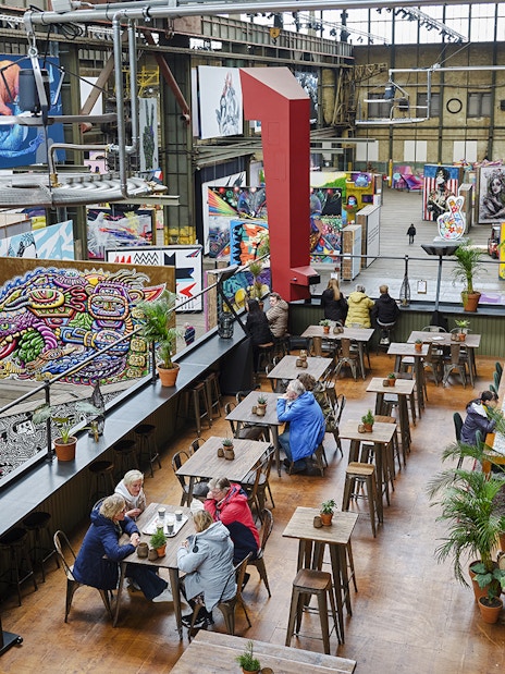 Cafe seating area inside Straat Museum with vibrant street art displays.