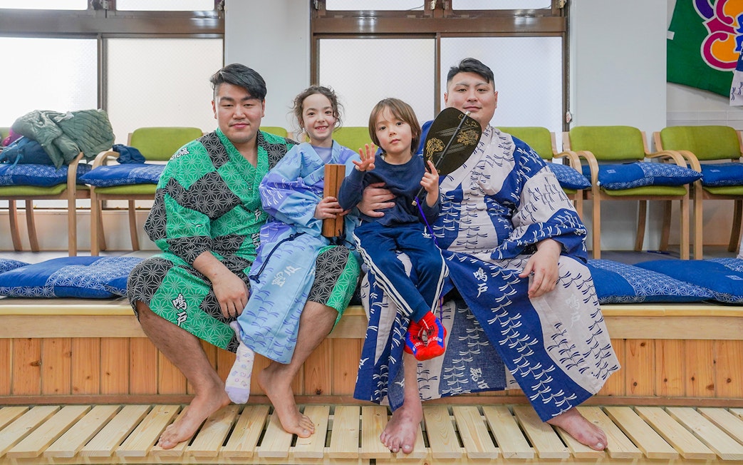Sumo wrestlers and children in traditional attire during Tokyo sumo wrestling experience.