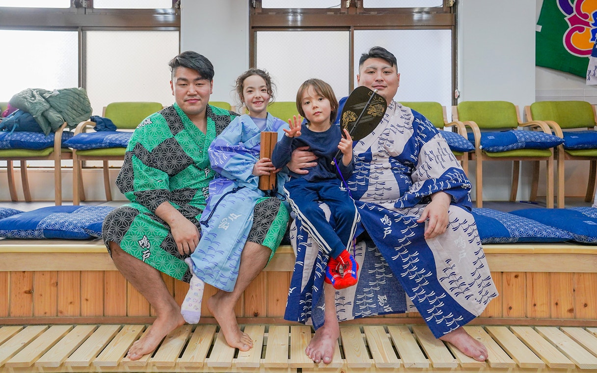 Sumo wrestlers and children in traditional attire during Tokyo sumo wrestling experience.