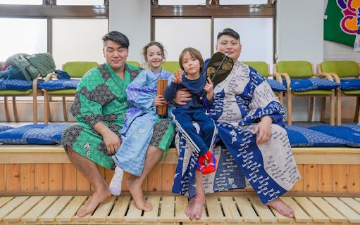 Sumo wrestlers and children in traditional attire during Tokyo sumo wrestling experience.