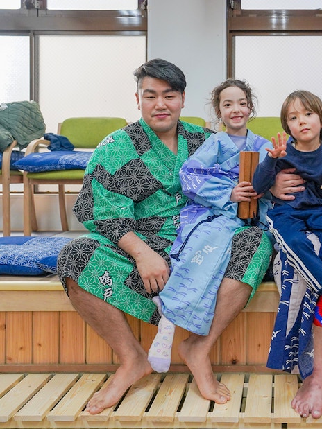 Sumo wrestlers and children in traditional attire during Tokyo sumo wrestling experience.