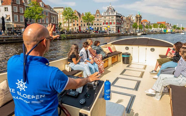 Open boat cruise on Haarlem canal with guide and tourists enjoying city views.