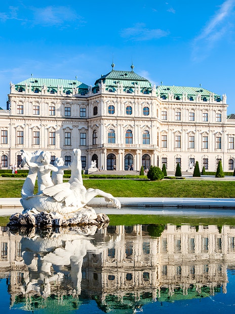 Belvedere Palace in Vienna, Austria, with a reflecting pool and sculpture in the foreground.