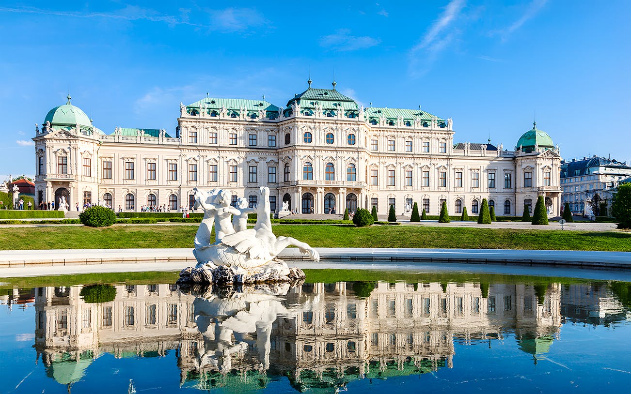 Belvedere Palace in Vienna, Austria, with a reflecting pool and sculpture in the foreground.