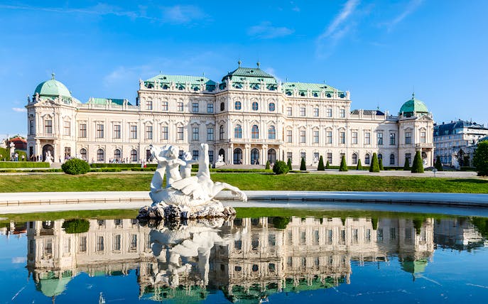 Belvedere Palace in Vienna, Austria, with a reflecting pool and sculpture in the foreground.