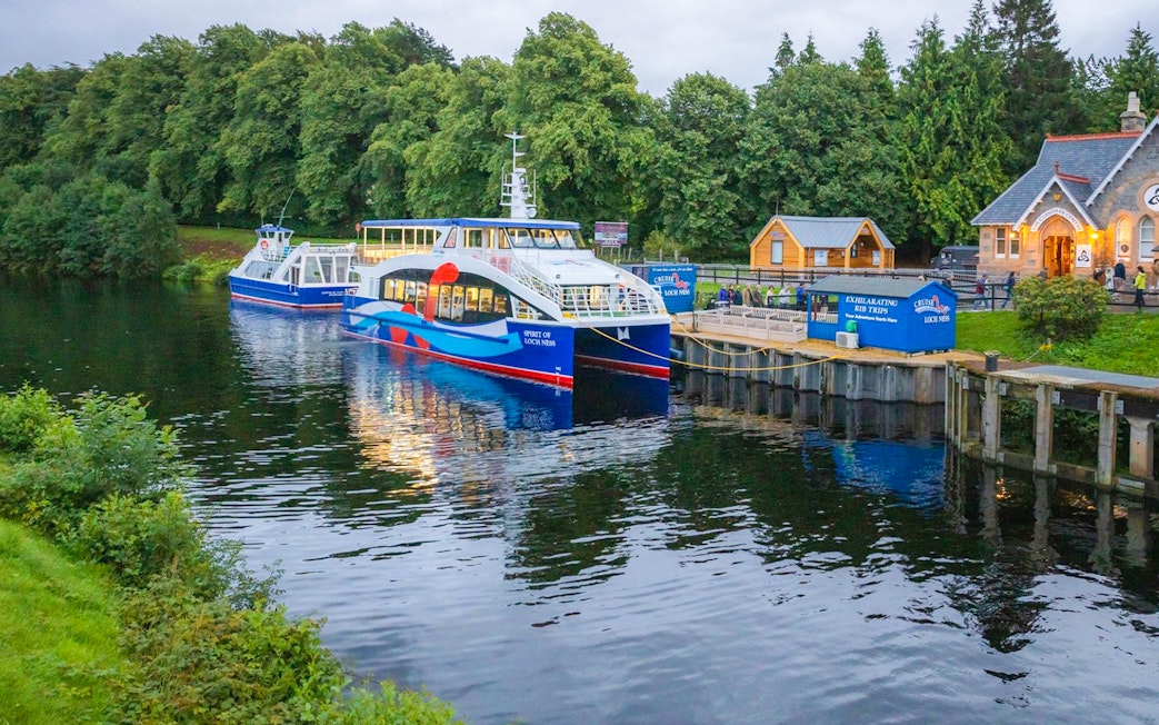 Cruise boat docked at Loch Ness with surrounding greenery, part of the Highlands tour from Edinburgh.