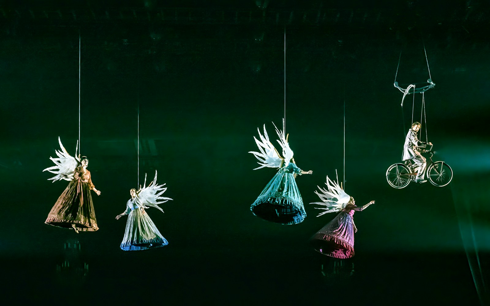 Acrobats suspended in air with wings and a bicycle during Cirque du Soleil's Corteo performance.
