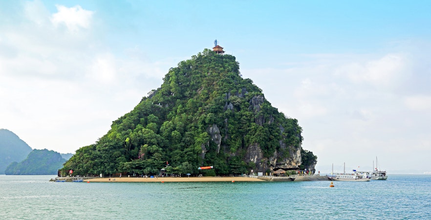 Dao Titop Island in Halong Bay with boats and limestone karsts in the background.