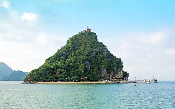 Dao Titop Island in Halong Bay with boats and limestone karsts in the background.