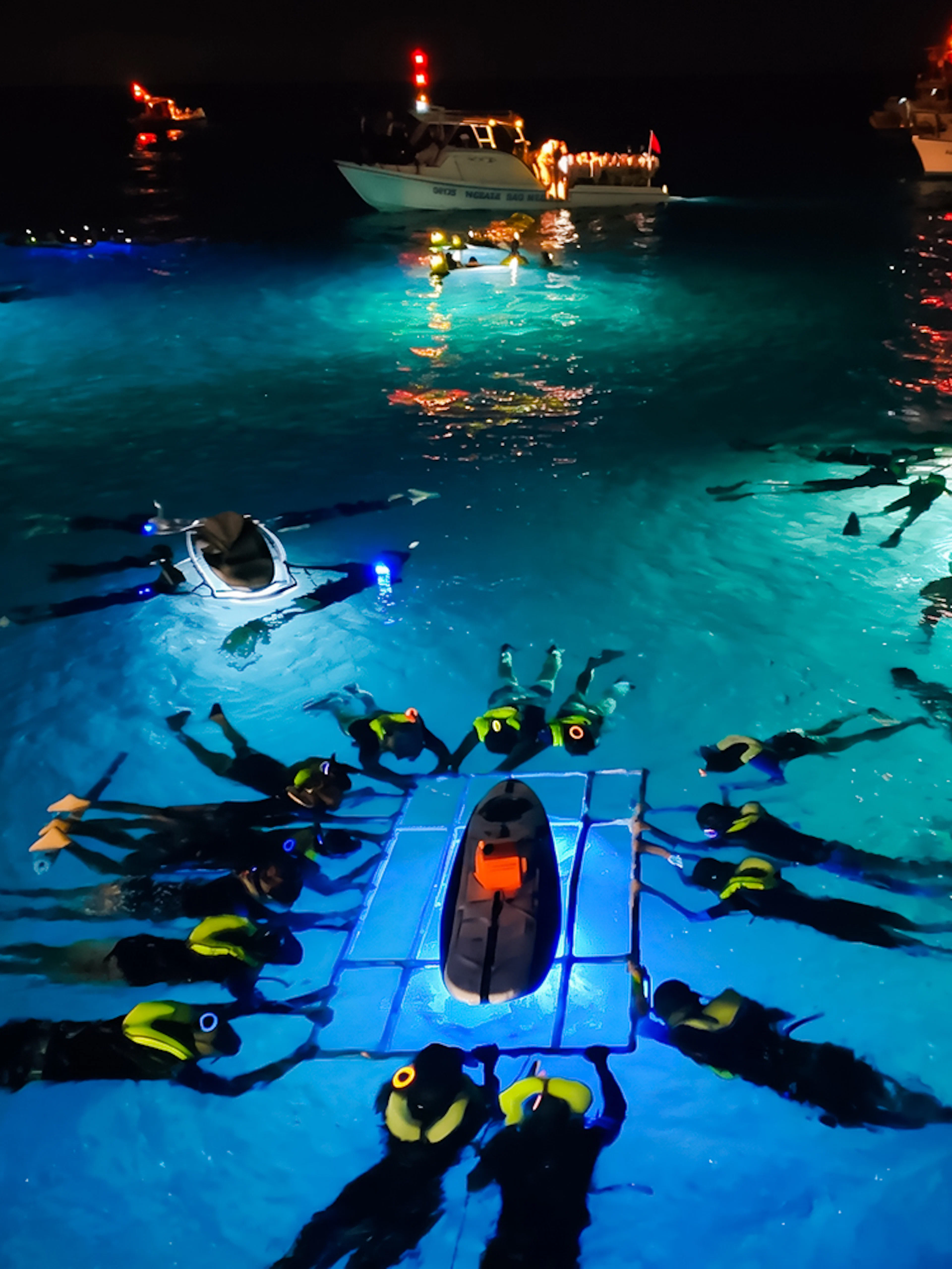 Snorkelers in illuminated water during Big Island Manta Ray Night Snorkel, Hawaii.