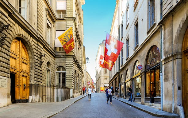 Street view in Geneva with Swiss and city flags, part of a 2-hour guided tour.