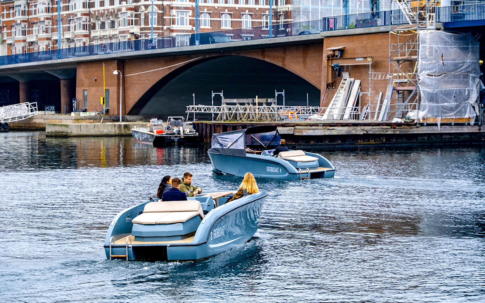 Harbour tour boat with guests in Copenhagen passing colorful waterfront buildings.