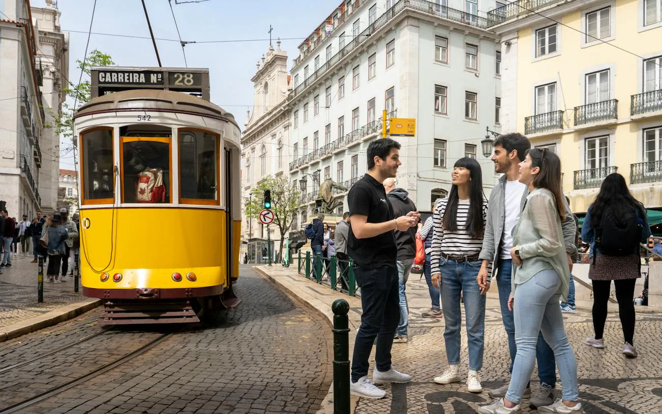 Lisbon tram and group of tourists in historic center during walking tour.