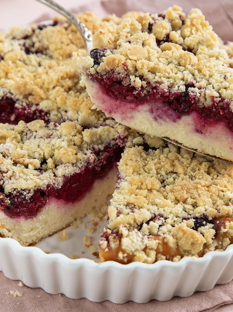 Ricotta and sour cherry tart with crumbly topping in a white dish.