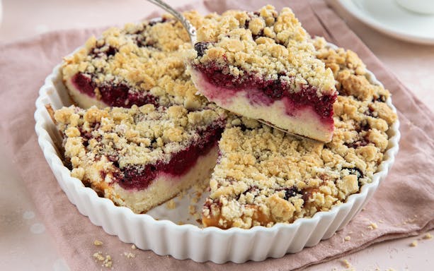 Ricotta and sour cherry tart with crumbly topping in a white dish.