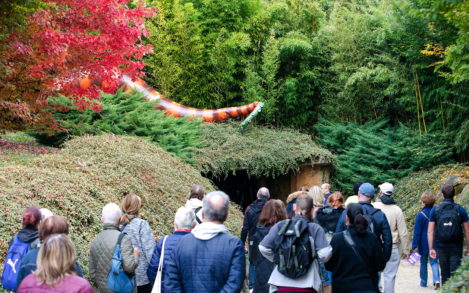 Visitors at ZooParc de Beauval during Halloween event, viewing a large snake decoration amidst lush greenery.
