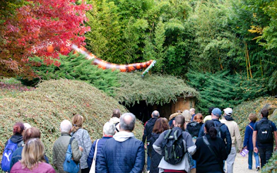 Visitors at ZooParc de Beauval during Halloween event, viewing a large snake decoration amidst lush greenery.