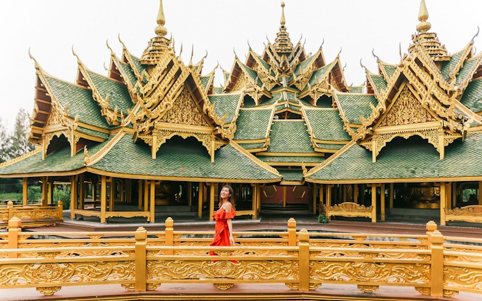 Woman in red dress at ornate pavilion in Ancient City, Bangkok.