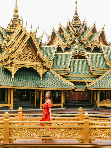 Woman in red dress at ornate pavilion in Ancient City, Bangkok.