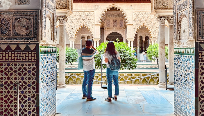 Ein Mann und eine Frau betrachten den Innenhof des Alcázar von Sevilla