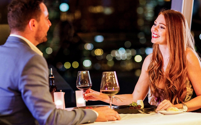 Couple dining with wine on Vivid Sydney dinner cruise.