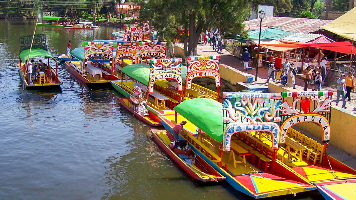 Colorful boats of Xochimilco near boarding point in Mexico City canal.