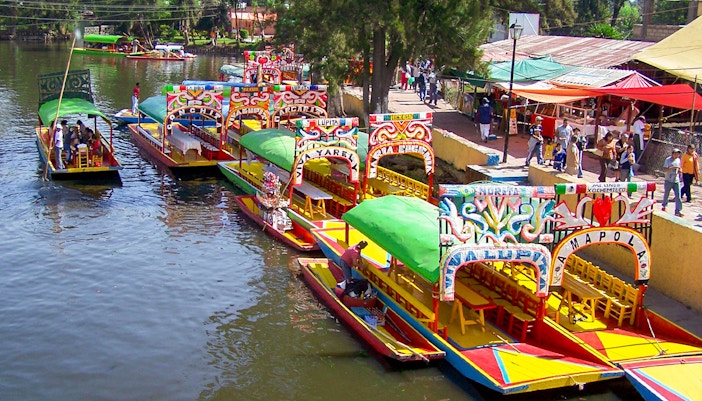 Colorful boats of Xochimilco near boarding point in Mexico City canal.